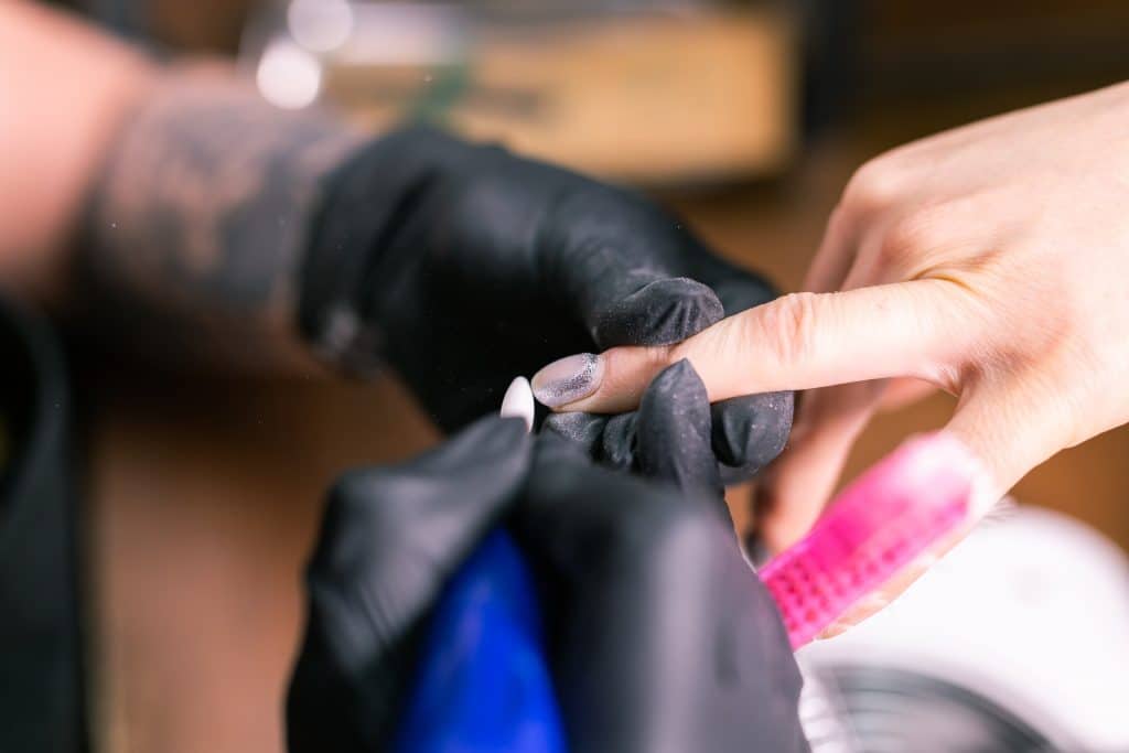 Close-up of hardware milling cutter for removing gel polish. Apparatus manicure in beauty salon. Manicurist with electric nail drill remove old gel from client nails. Process of replacing shellac.