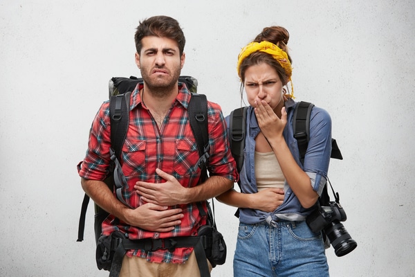 Food poisoning, nausea and sickness concept. Portrait of young man and woman tourists feeling stomach ache, suffering from diarrhea after they ate some exotic food during journey in Asian country